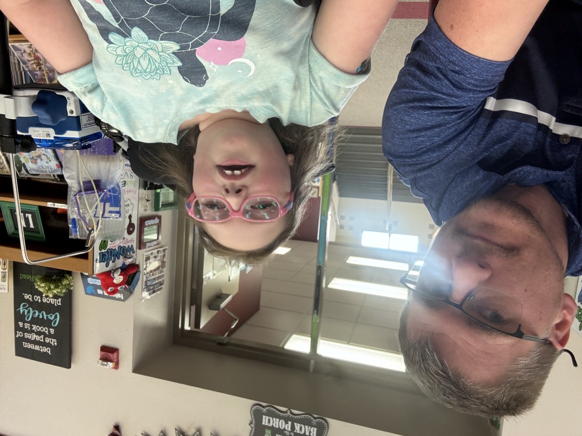Sophia with Dad and medical equipment nearby during a school visit