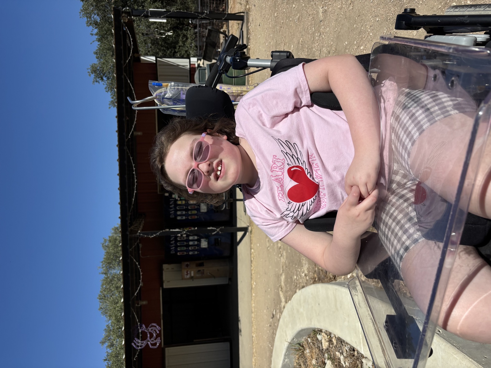 Sophia smiling outdoors in her wheelchair in 2025