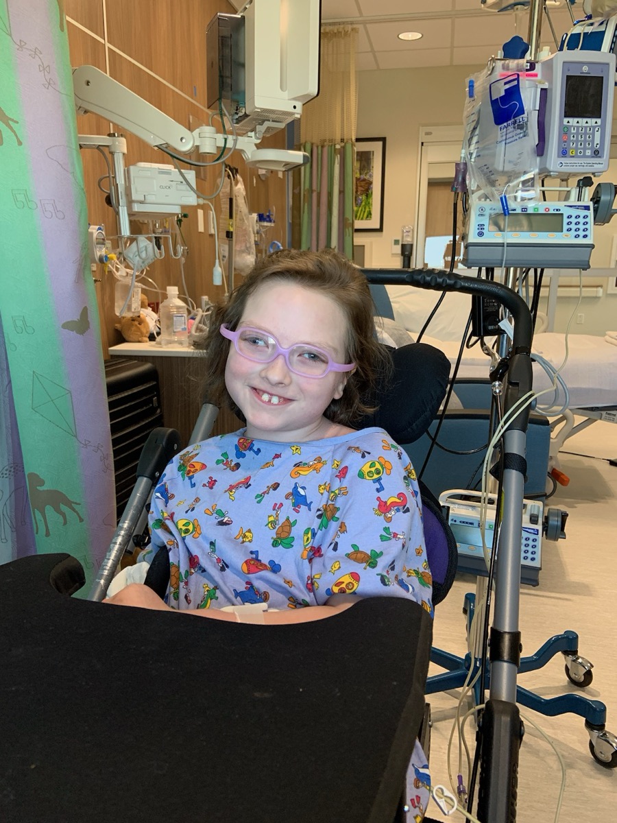 Sophia smiling in her wheelchair during a hospital stay in 2023